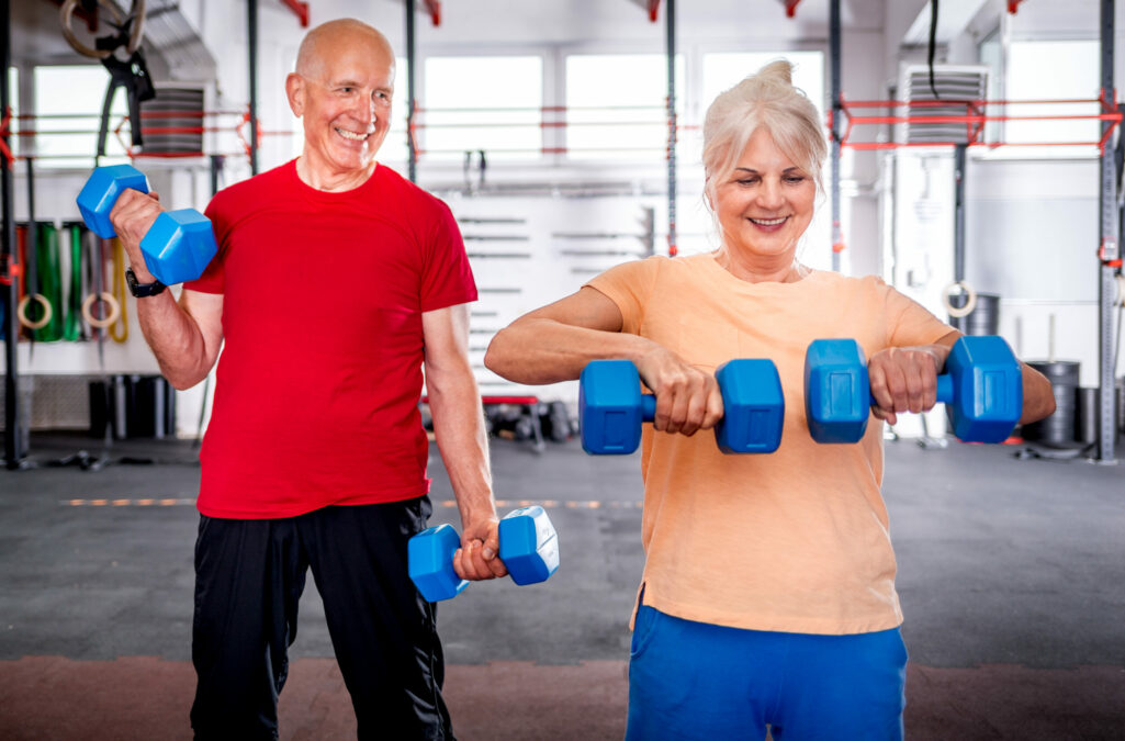 Senior people with dumbbells doing exercises at the gym